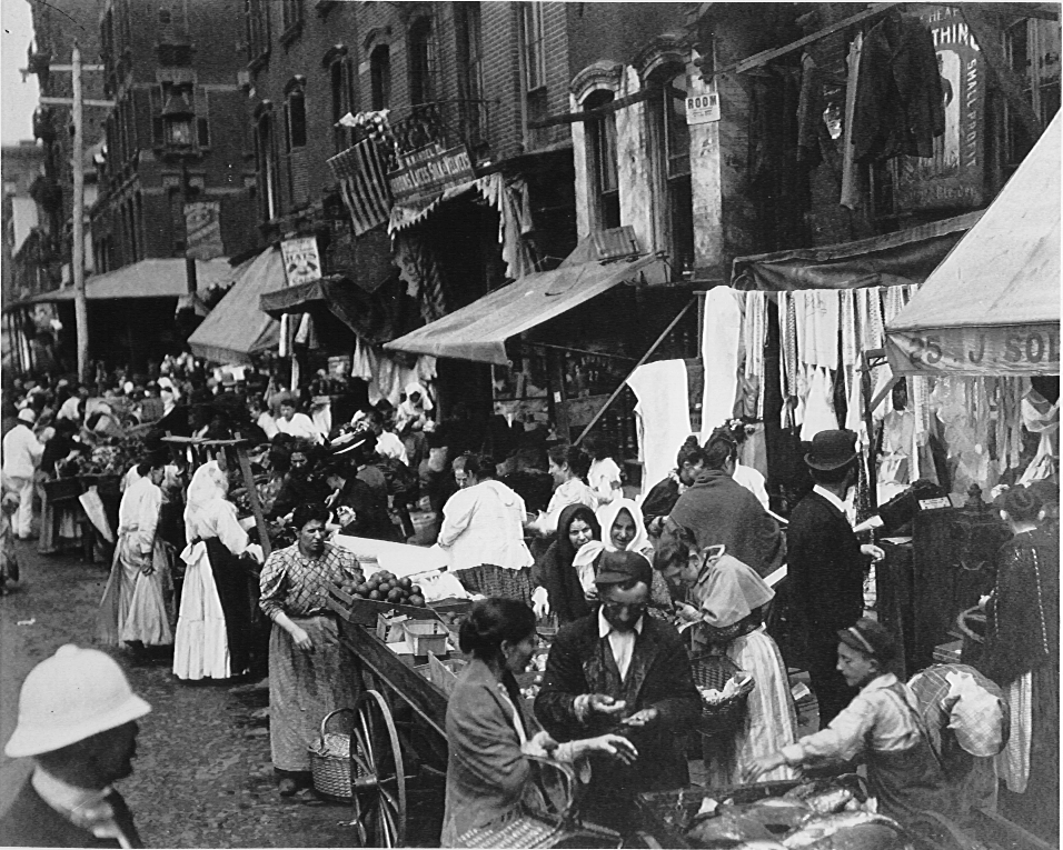 Shoppers on a busy street buying food and browsing other items being sold in pushcarts and stalls