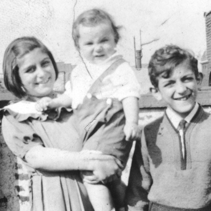 Black and white photo of a young Josephine Baldizzi carrying a baby with a young Johnny Baldizzi on the right, all smiling