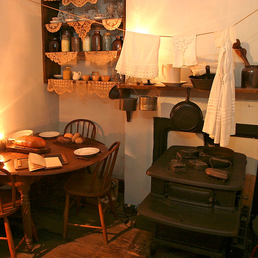 Small table with bread and two plates in a corner of Gumpertz family kitchen next to an iron stove