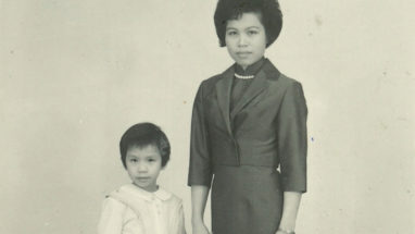Black and white photo of Ms. Wong and Yat Ping. Ms. Wong wears skirt suit and pearls, and Yat Ping wears a collared dress