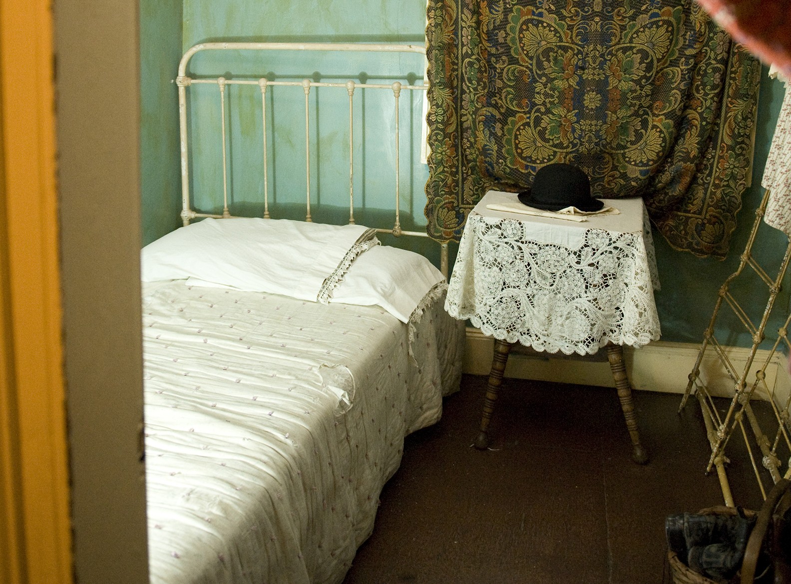 Small bed and stool inside a recreated tenement apartment.