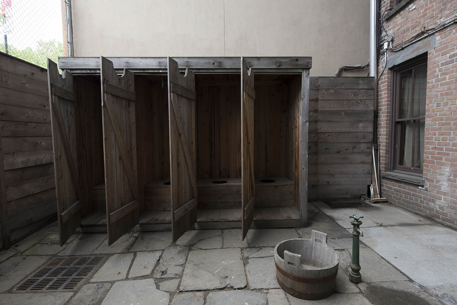 A wooden outhouse with four stalls stands with all its doors open