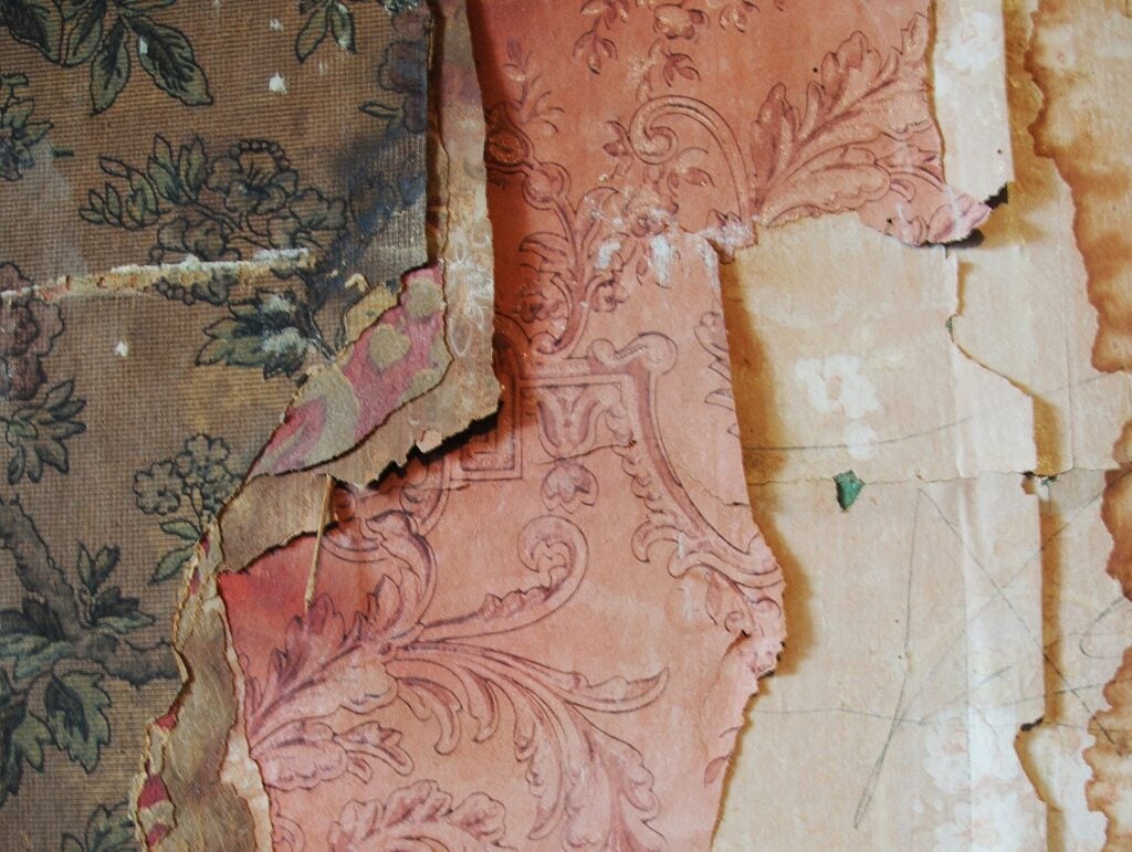 Close up view of various colorfully patterned layers of old wallpaper
