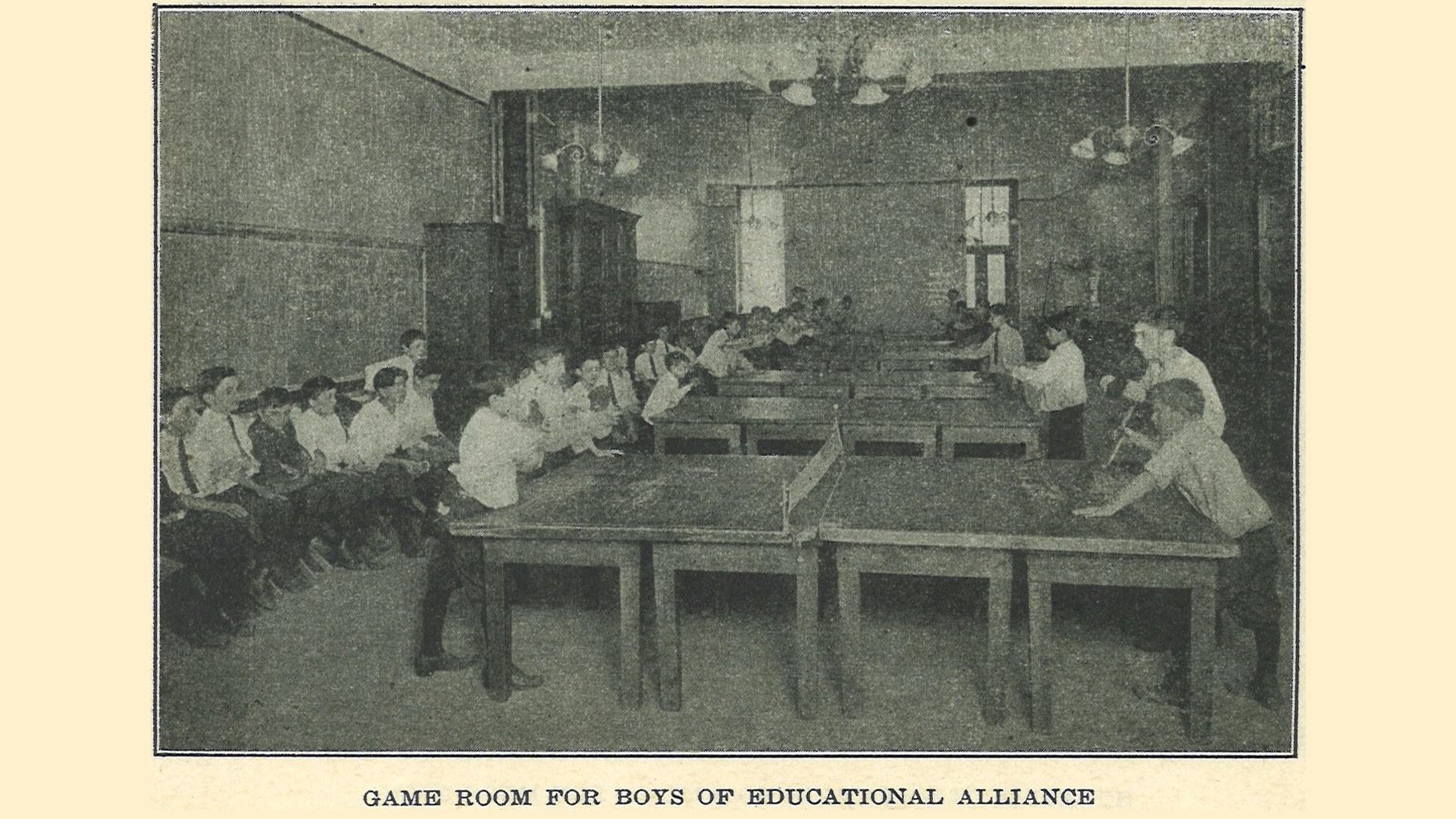 Old black and white photo of young boys playing table tennis in a game room at the Education Alliance