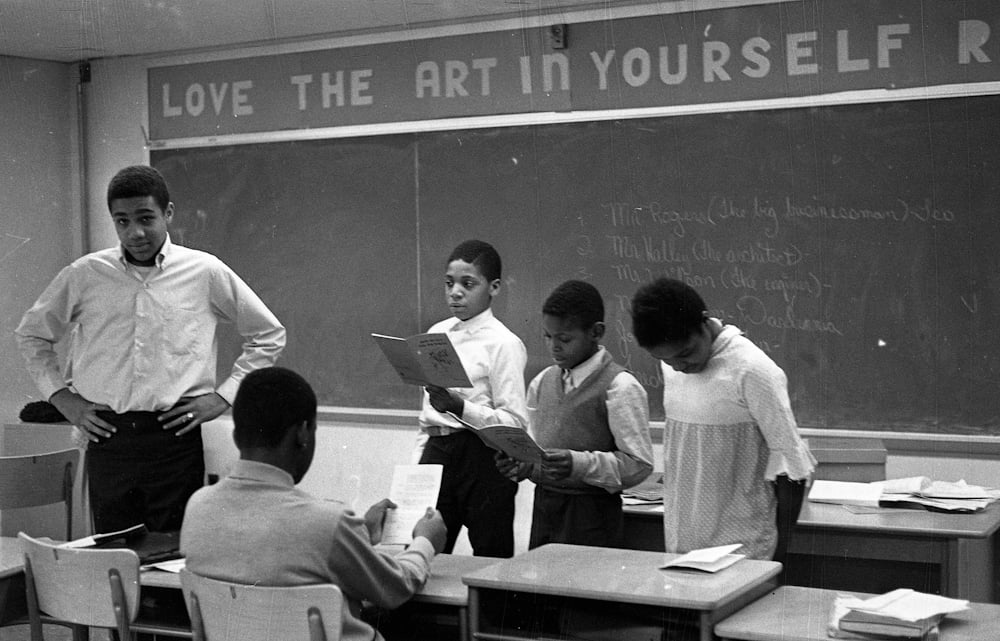 Black and white photo of black students in classroom standing in the front of the class.